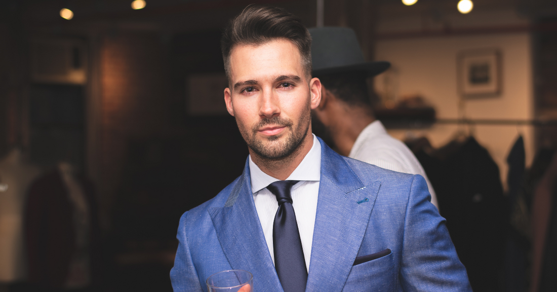 A stylish man in a tailored blue suit with a white shirt and navy tie, showcasing a classic formal look.