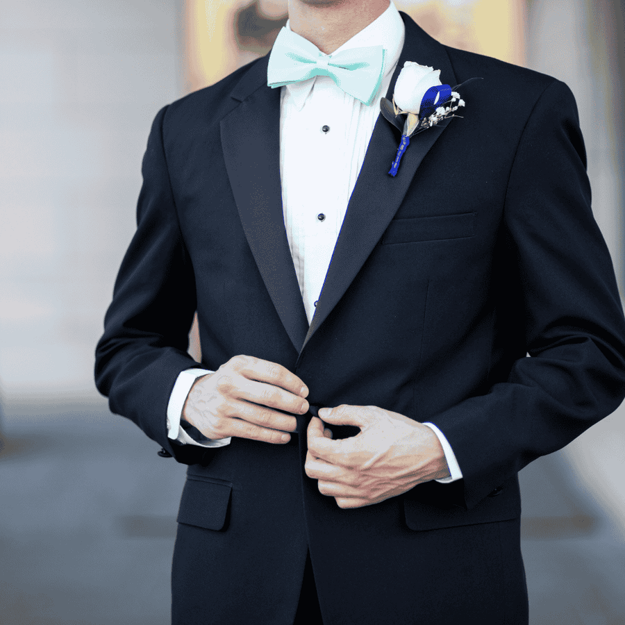 Close-up of man wearing black tuxedo with bow tie and boutonniere formal wedding outfit